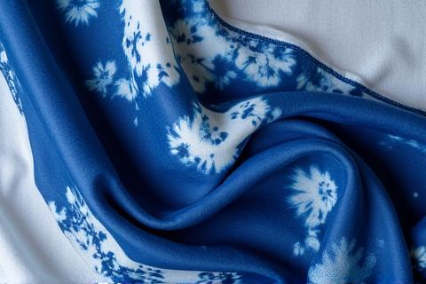 이전 워크숍. 쪽빛 염색된 실크 스카프를 펼쳐 보여주는 이미지.